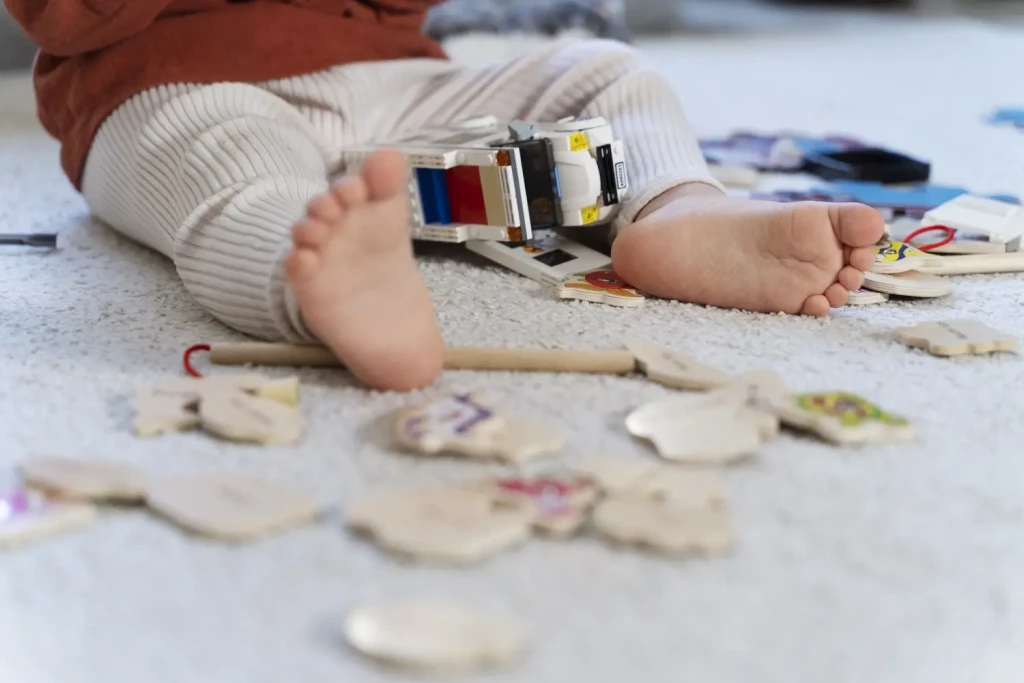 Bébé assis sur un tapis jouant avec des jouets éducatifs en bois colorés