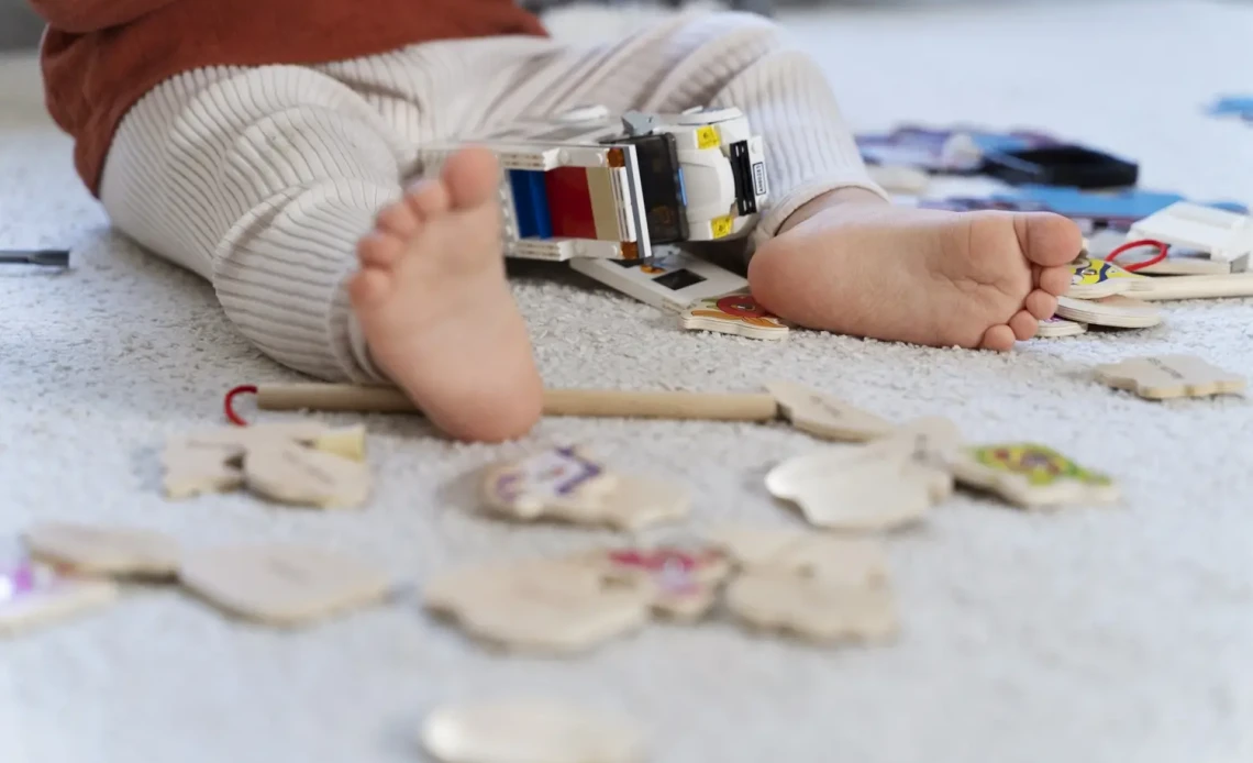Bébé assis sur un tapis jouant avec des jouets éducatifs en bois colorés