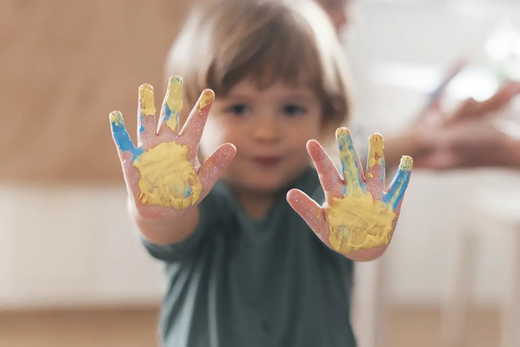 Enfant montrant ses mains couvertes de peinture colorée après une activité créative