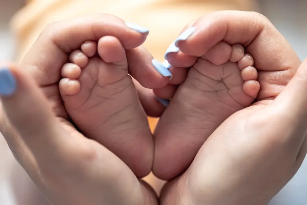 Pieds de bébé formant un cœur dans les mains d’un parent