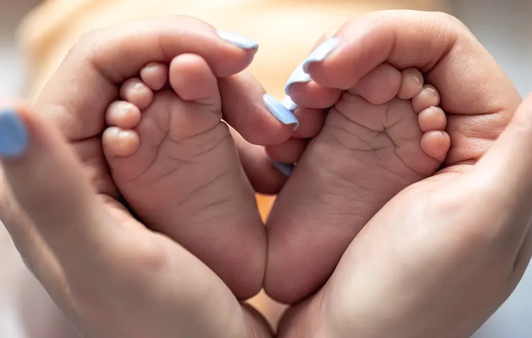 Pieds de bébé formant un cœur dans les mains d’un parent